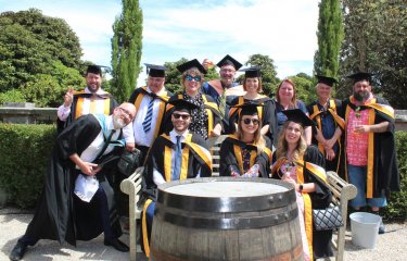 A group of graduating students wearing gowns gather together 