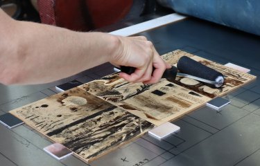 Someone inking a wood cut for mokulito