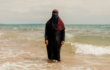 Woman wearing hijab standing in the sea. Portrait of Britain 2023 winning photo by Peter Flude. 