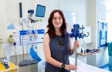 Image of person holding an IV drip holder in a hospital