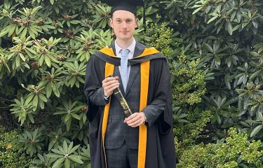 User Experience Design graduate Paul Phillips at graduation wearing a gown and mortar board