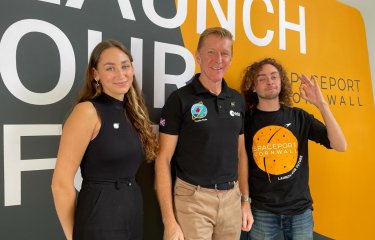 Graduate Rachel Harrison and student Ben Pisacane stand either side of Time Peake in front of backdrop that reads 'Launch our future'.