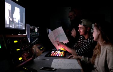 Two Film students at Falmouth University sat behind a large screen, editing