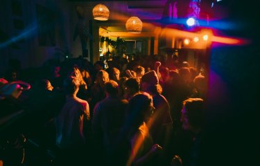 Dark photo of a crowd of people enjoying a live band.