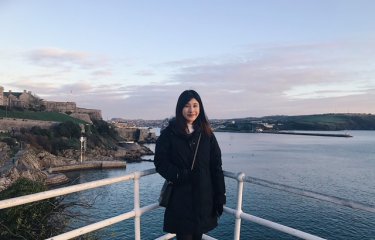 A woman poses in front of the ocean