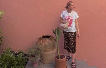 A woman stood outside a pink building 
