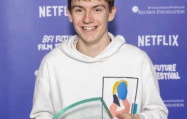 Will Wightman - dressed in a white hoodie - poses with his Best Director Award