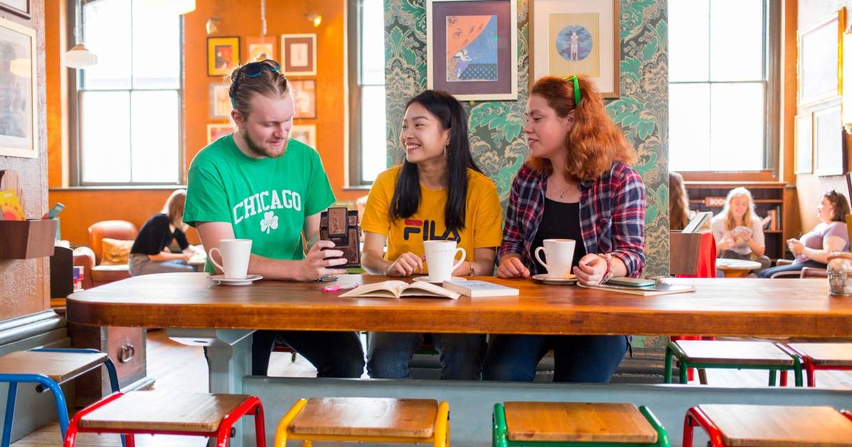 Brightly dressed students having coffee in brightly decorated cafe.