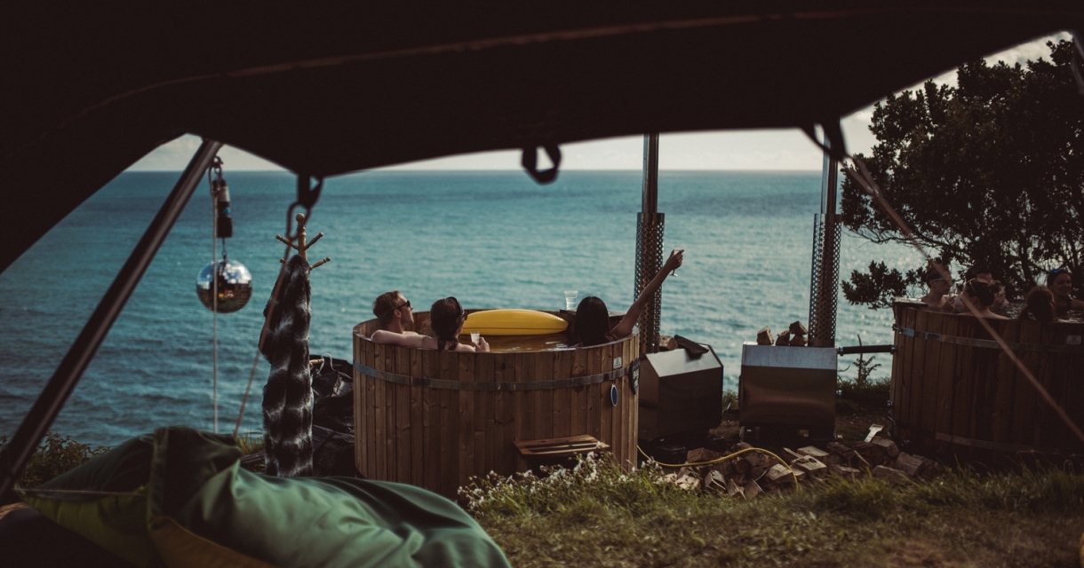 Group relaxing in a wooden hot tub with incredible sea view.