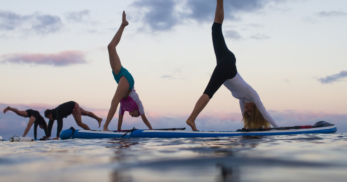 Group of paddle boarders doing yoga on boards.