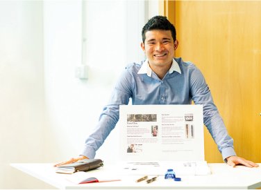 Business & Entrepreneurship student standing at a display table, smiling