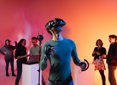 Male student wearing a virtual reality headset with five other students in the background