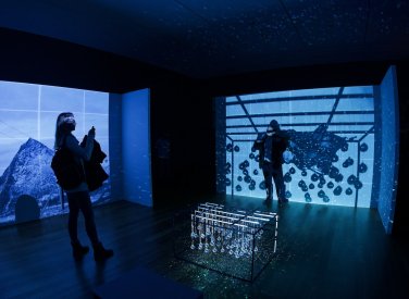 Two people standing in a dark room with blue projections