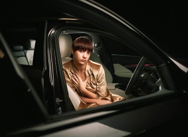 A model wearing gold sitting in a black car