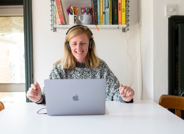 A woman smiling while looking at her laptop