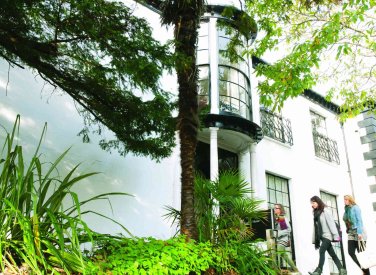 A white building behind greenery