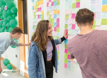 People standing by board with ideas pinned to it