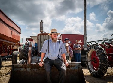 A man sitting on the front of a tractor