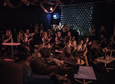 A busy venue with people watching a show and clapping