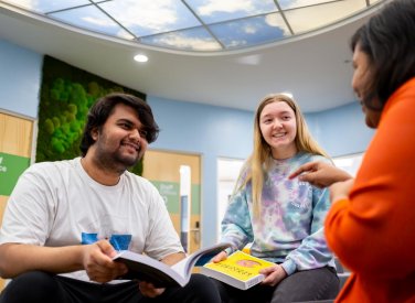 Three business students sat down, talking at Falmouth University