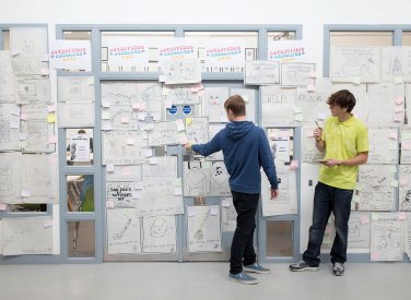 Students standing at a wall full of ideas written on paper