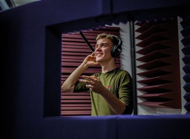 Student holding hand to ear in film dubbing suite