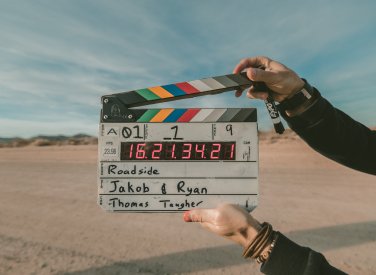 A film slate being held up against an empty field 