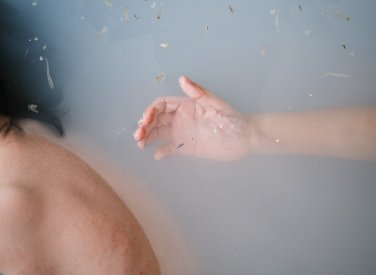 A photograph of a hand in a bathtub of water