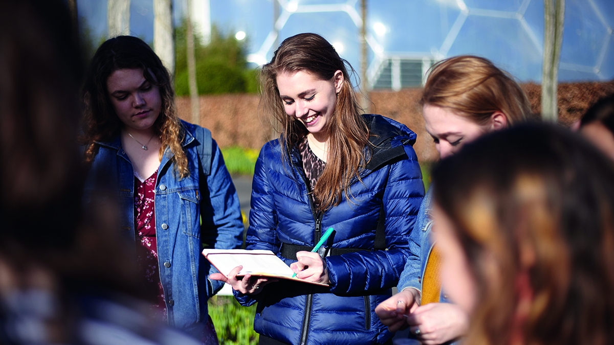 Group of students smiling and looking at notes at the Eden Project.