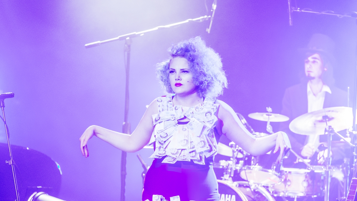 Actor on stage with band lit with purple light.