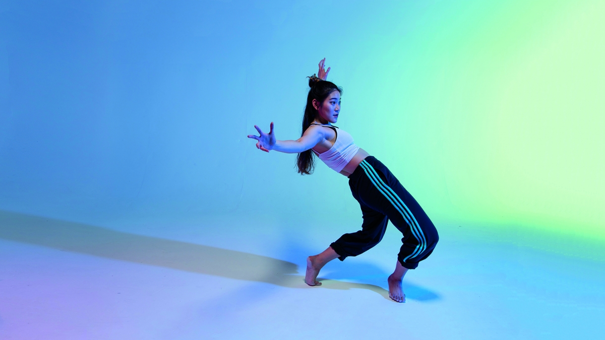AMATA student performs solo Solo performer dances against multi-coloured backdrop