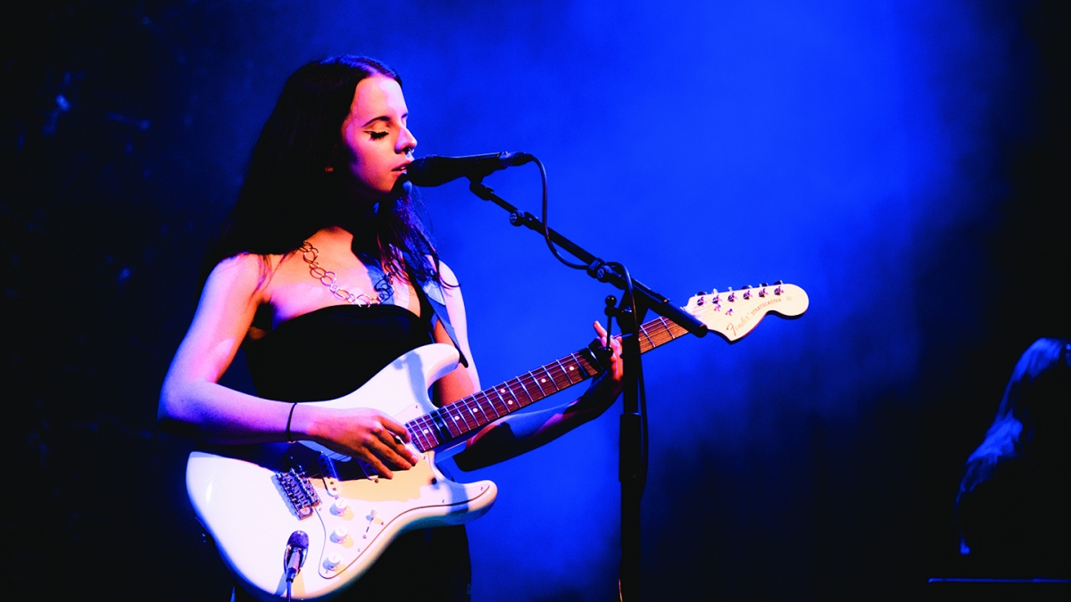 Popular Music Student Performing Popular Music student singing and playing guitar on stage