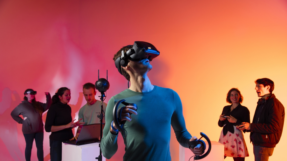 Male student wearing a virtual reality headset with five other students in the background