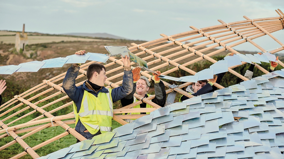 Architecture students laying a roof on a structure