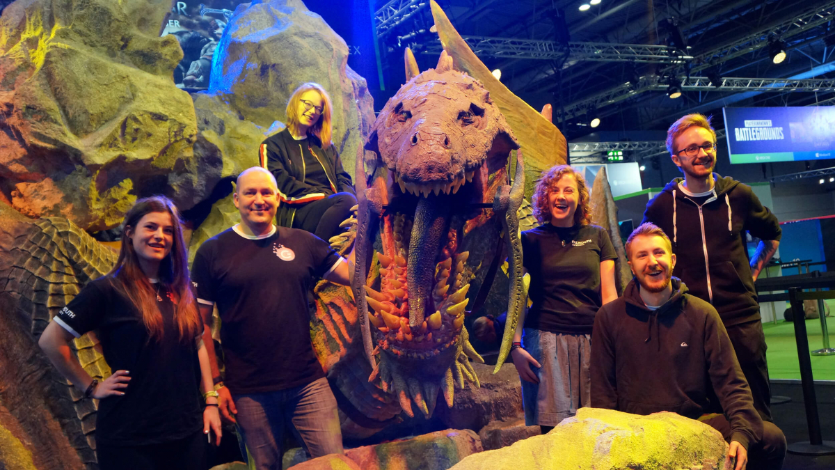 Falmouth University Games Academy students standing in front of a large dinosaur model