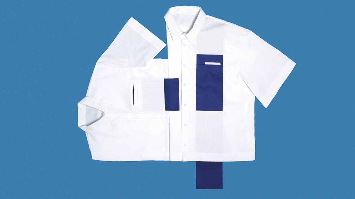 Flat lay of white shirt with blue rectangle patch on blue background.