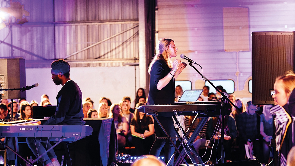 Music students on stage singing and playing keyboard.
