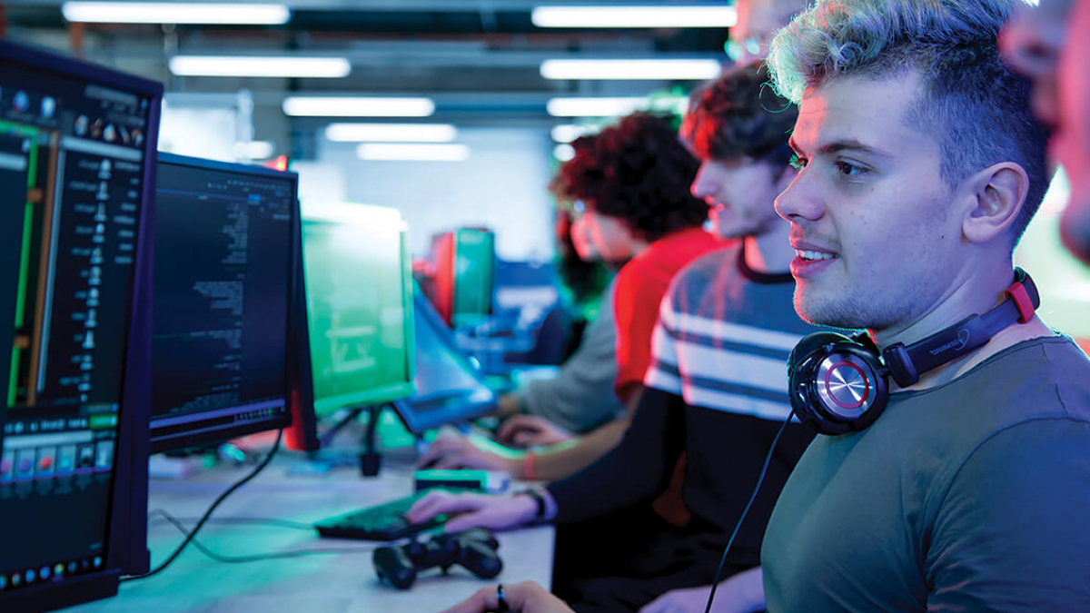 A student coding at a computer, wearing headphones