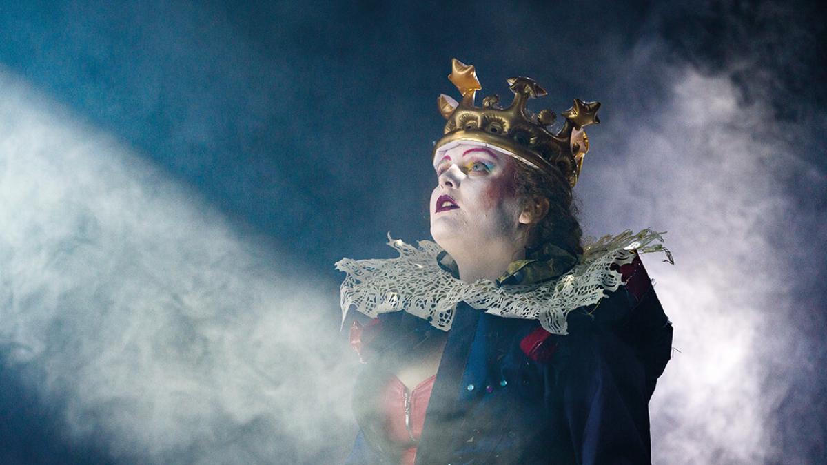 A Musical Theatre actor in stage makeup, wearing a ruff and crown