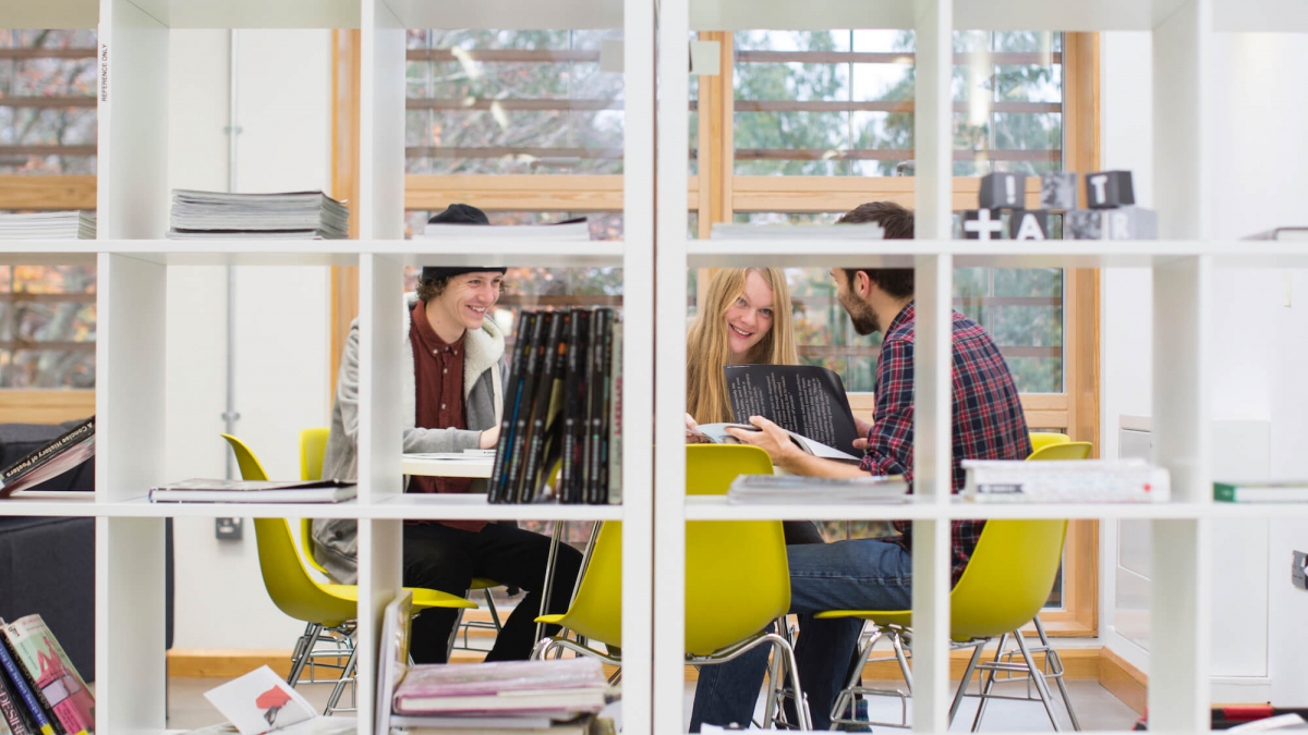 Students viewing through a square shelving unit.