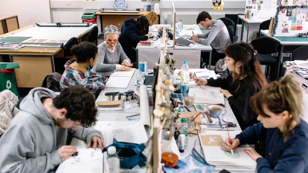Students in busy studio at desks drawing.