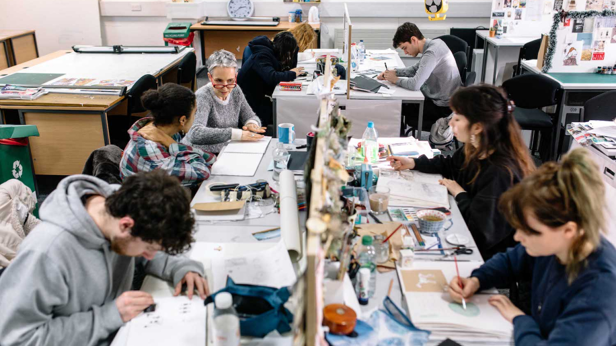 Illustration students in busy studio at desks drawing.