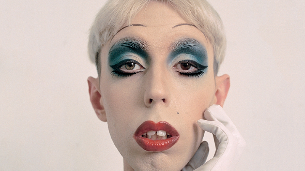 Headshot of model in heavy make up, blue shaded eyes, red lips and white hair and skin.