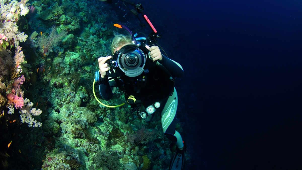 Student underwater pointing camera at the photographer.