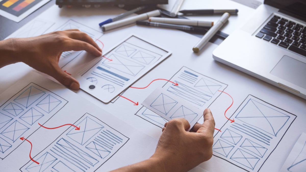 User Experience Design Ma 2022 website layout plans on paper with hands and pens