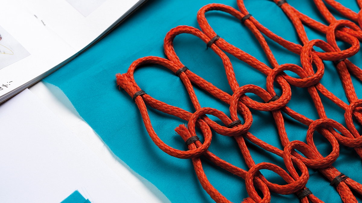 Red cord woven in pattern on a turquoise blue fabric.