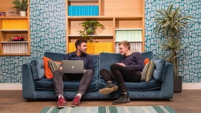 Falmouth advertising alumni Ben Fallows and Matt Deacon chatting on a sofa.