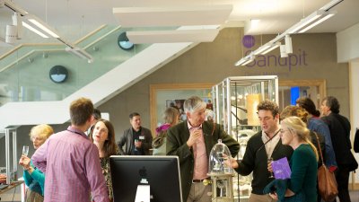 People standing round and chatting at an exhibition at Falmouth University