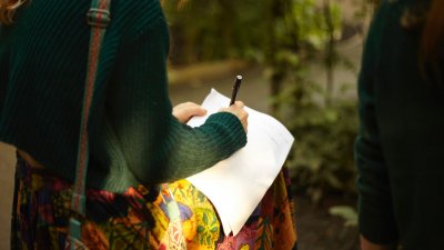 A girl in a green jumper writing on white paper