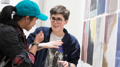 Two Falmouth University students discussing images at an exhibition.